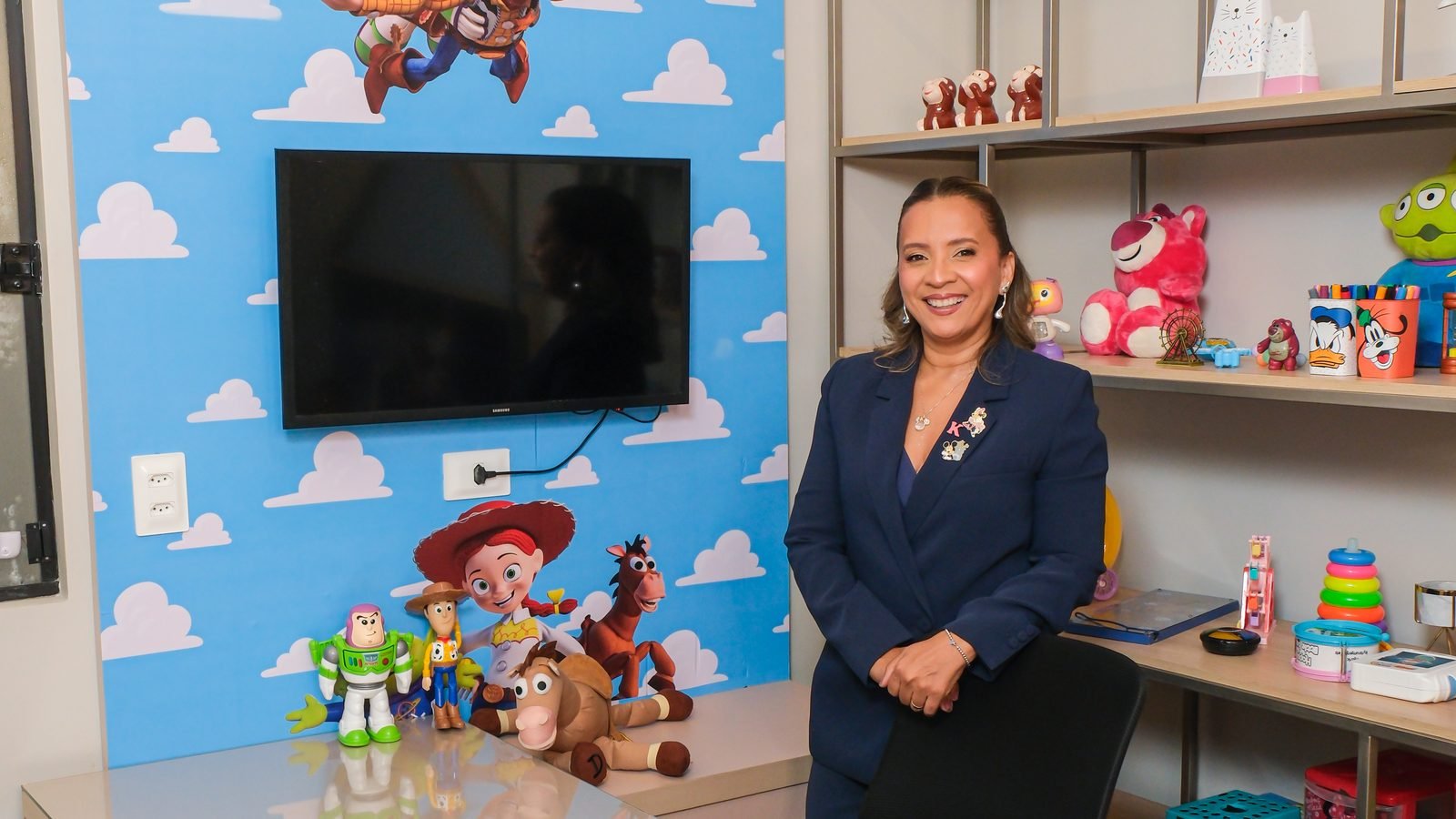 Kennya Martins, neuropsicóloga, na sala de atendimento infantil, ao lado da estante de brinquedos