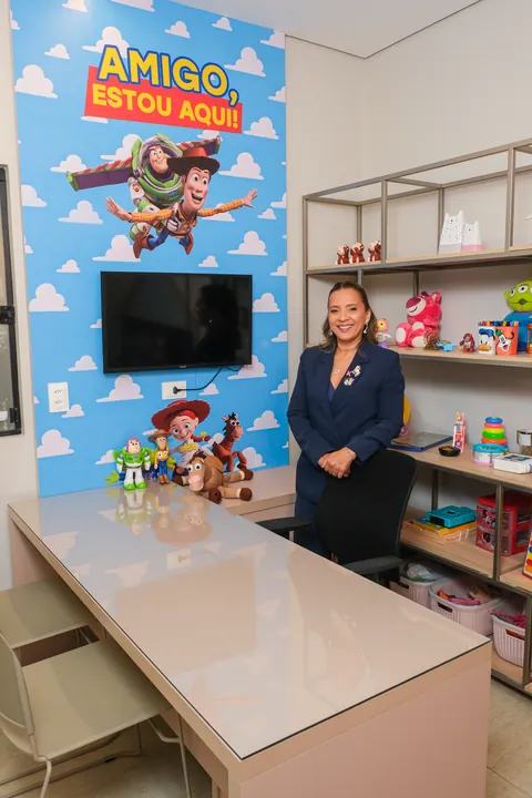 Kennya Martins em pé ao lado da estante de brinquedos da sala de atendimento infantil, em Teresina