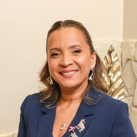 Kennya Martins, psicóloga e neuropsicóloga, sorrindo, de blazer azul-marinho