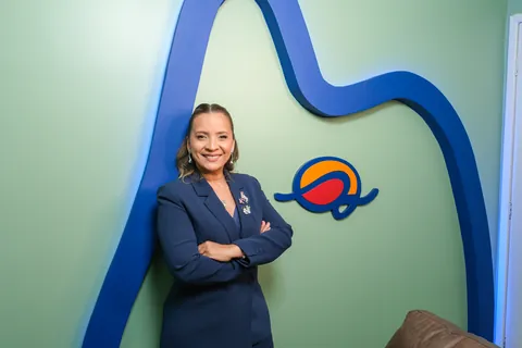 Kennya Martins, neuropsicóloga, de braços cruzados ao lado do símbolo do Instituto Mundo de Dentro